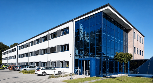 Außenansicht des Proalpha-Firmengebäudes in Weilerbach bei Kaiserslautern mit moderner Glasfassade, Bürotrakt, Parkplatz und Grünfläche.
