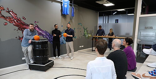 Employés de la société ECKD GmbH dans l'espace découverte « Arena » avec tribune et écran de projection lors d'un atelier créatif ou d'une réunion.