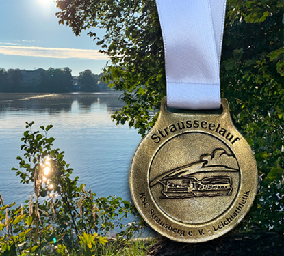 Medaillenaufnahme vom Strausseelauf 2025 vor dem Straussee, glänzend im Sonnenlicht